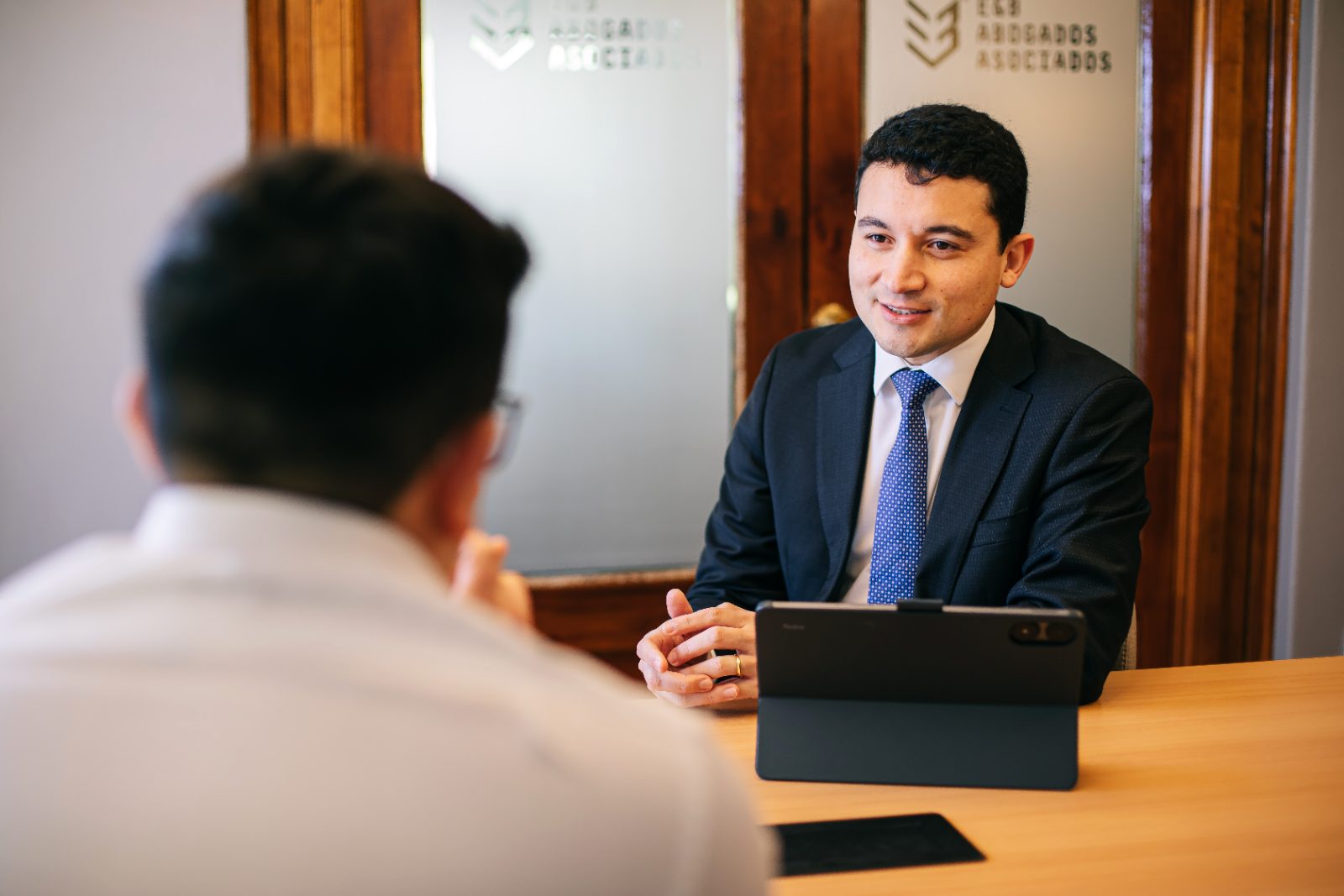 Abogado de E&B Abogados Asociados revisando antecedentes con un cliente en la sala de reuniones
